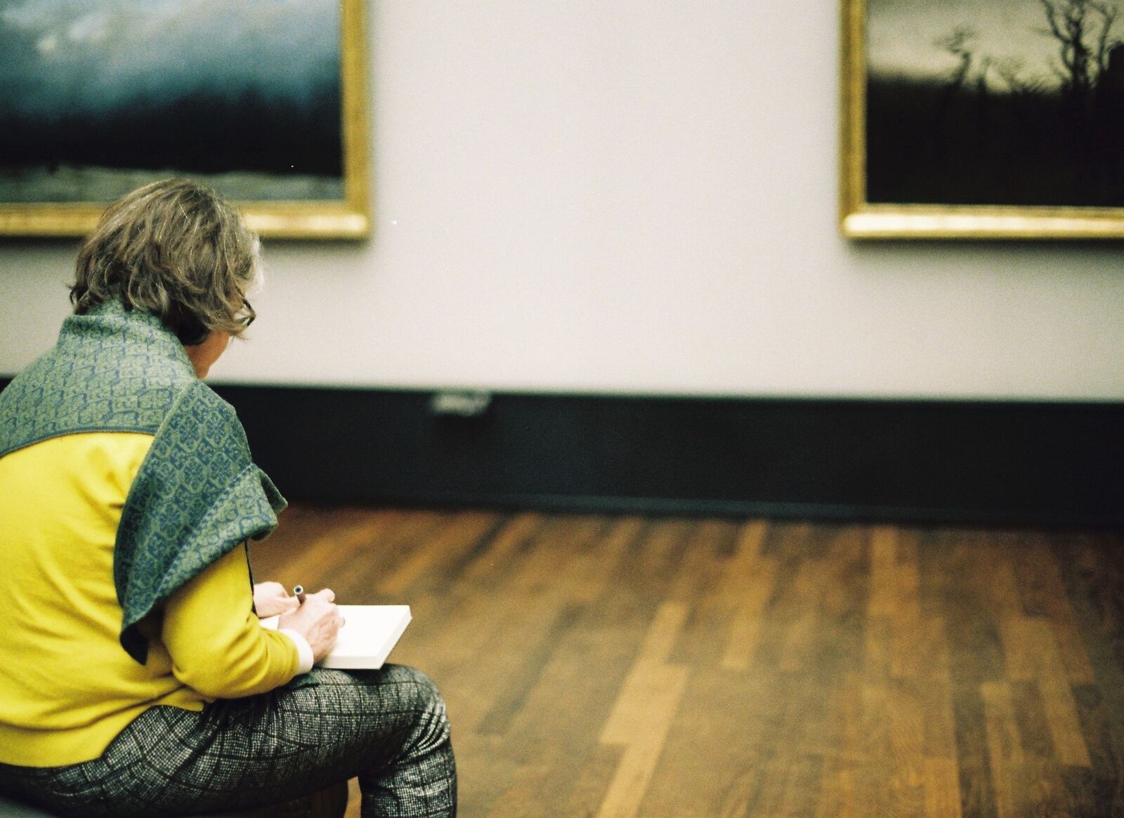 Une visiteuse dessine devant des œuvres dans une galerie d’art