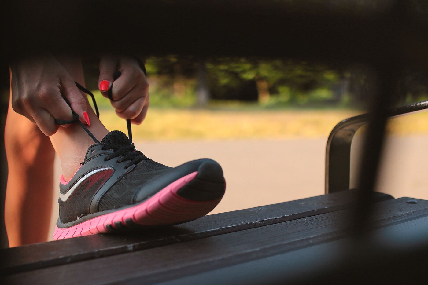Une personne prépare ses chaussures de course sur un banc extérieur