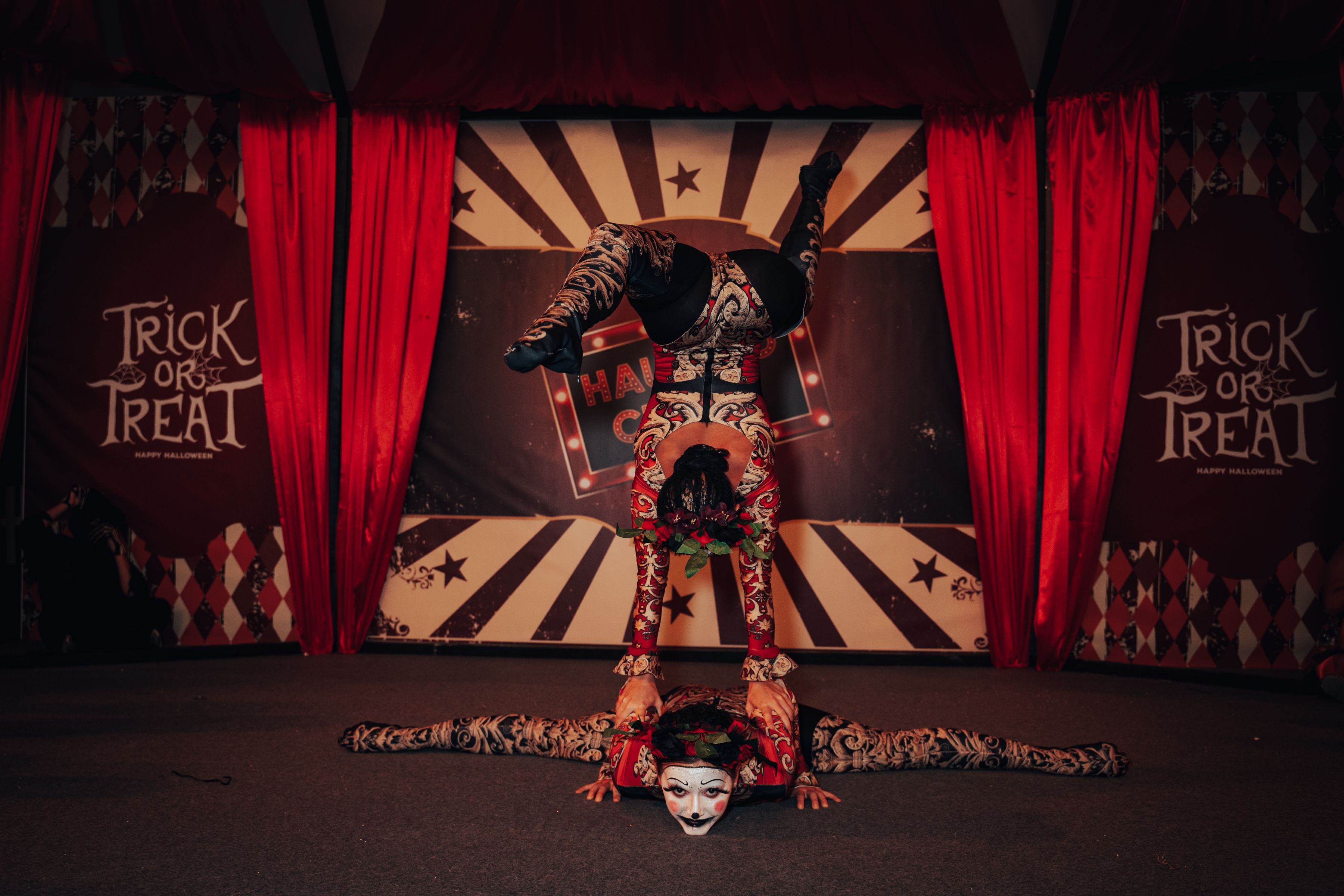 Deux acrobates en costumes colorés se produisent sous un chapiteau éclairé.