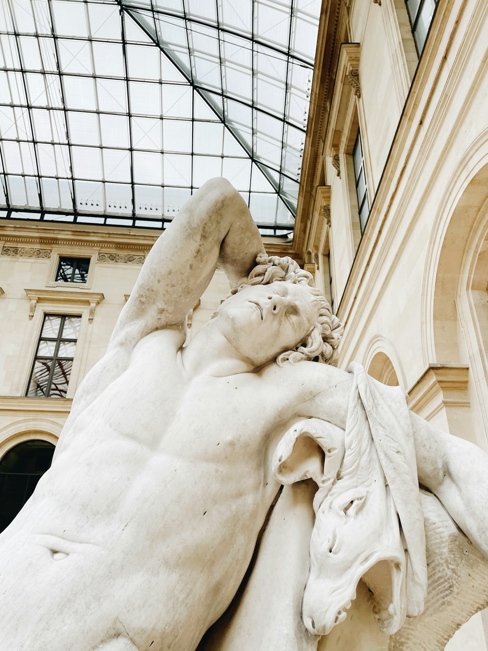 Vue intérieure d'une galerie de sculptures sous verrière au musée du Louvre