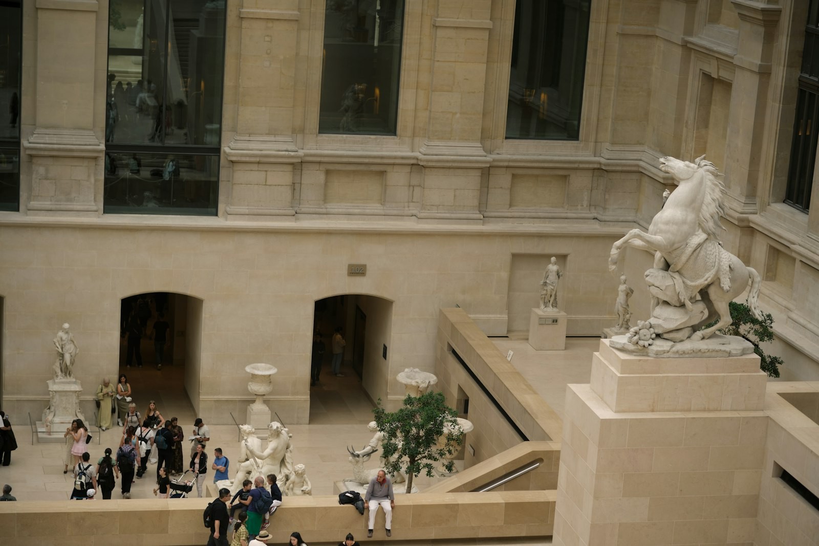 Sculptures de marbre présentées sous une verrière dans une cour intérieure du musée du Louvre