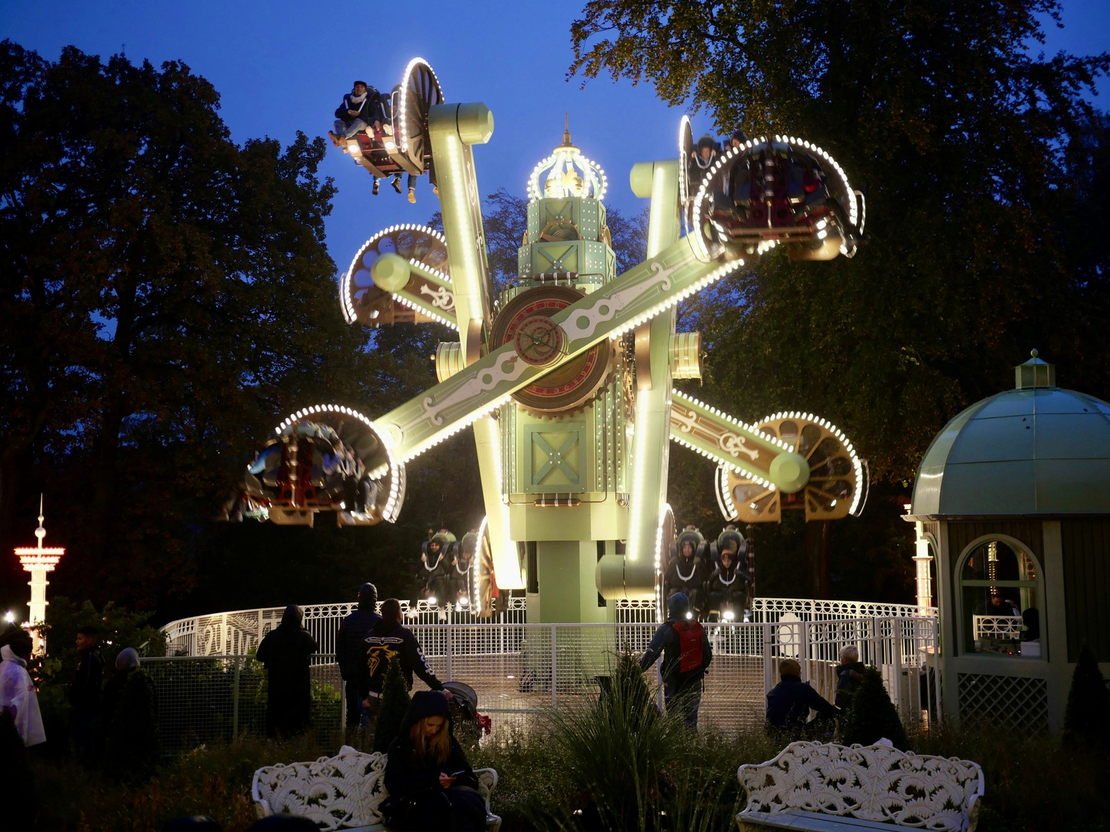 Foule déambulant au pied des attractions foraines et manèges illuminés de nuit