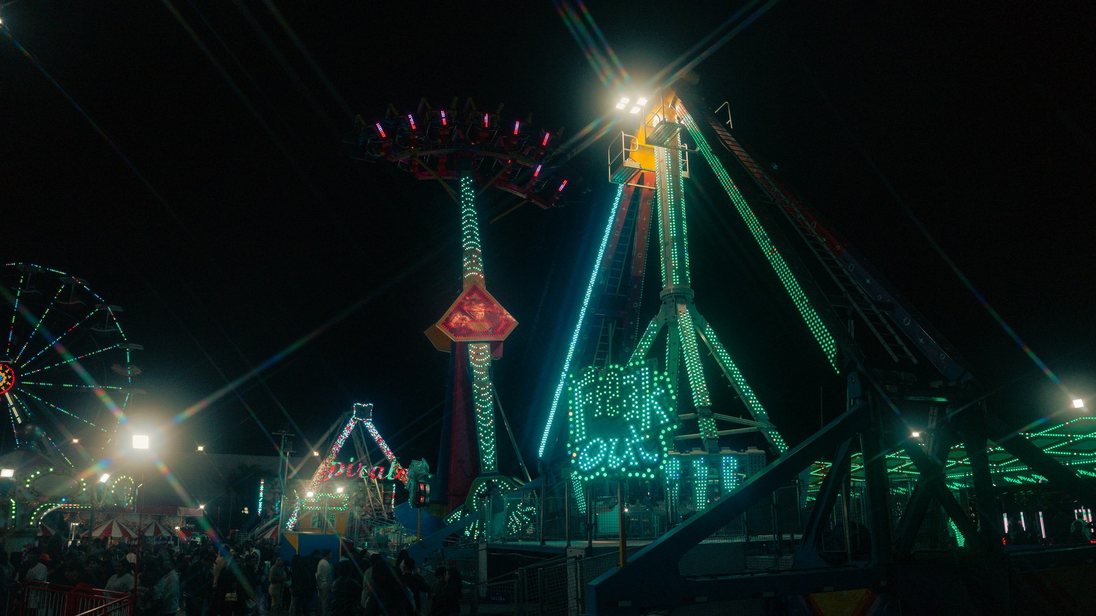 Attractions de fête foraine illuminées de nuit sous un ciel noir