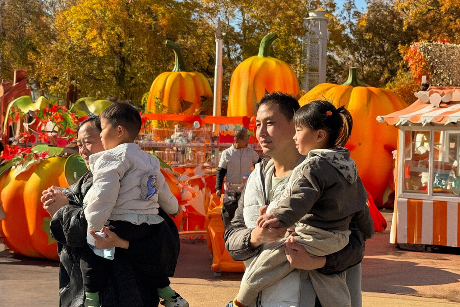 Visiteurs et décors de fête d’automne dans les allées d’un parc de loisirs