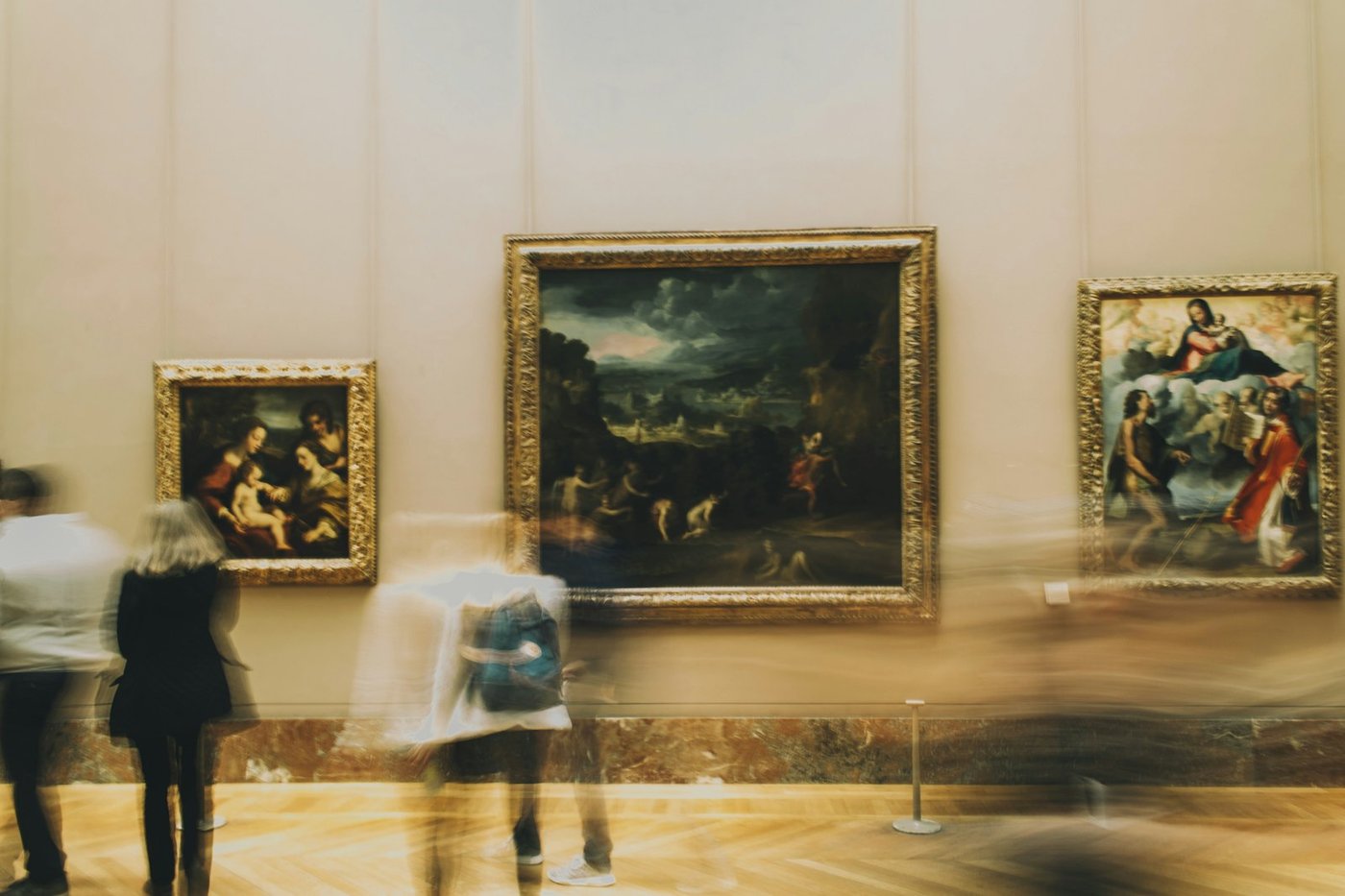 Visiteurs contemplant des tableaux classiques dans une grande galerie du musée du Louvre