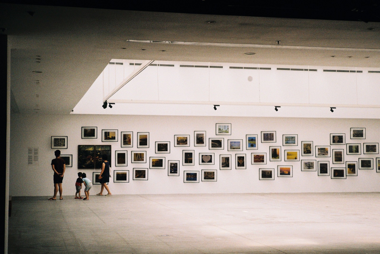 Visiteurs dans une galerie d’exposition d’art contemporain avec tableaux accrochés aux murs